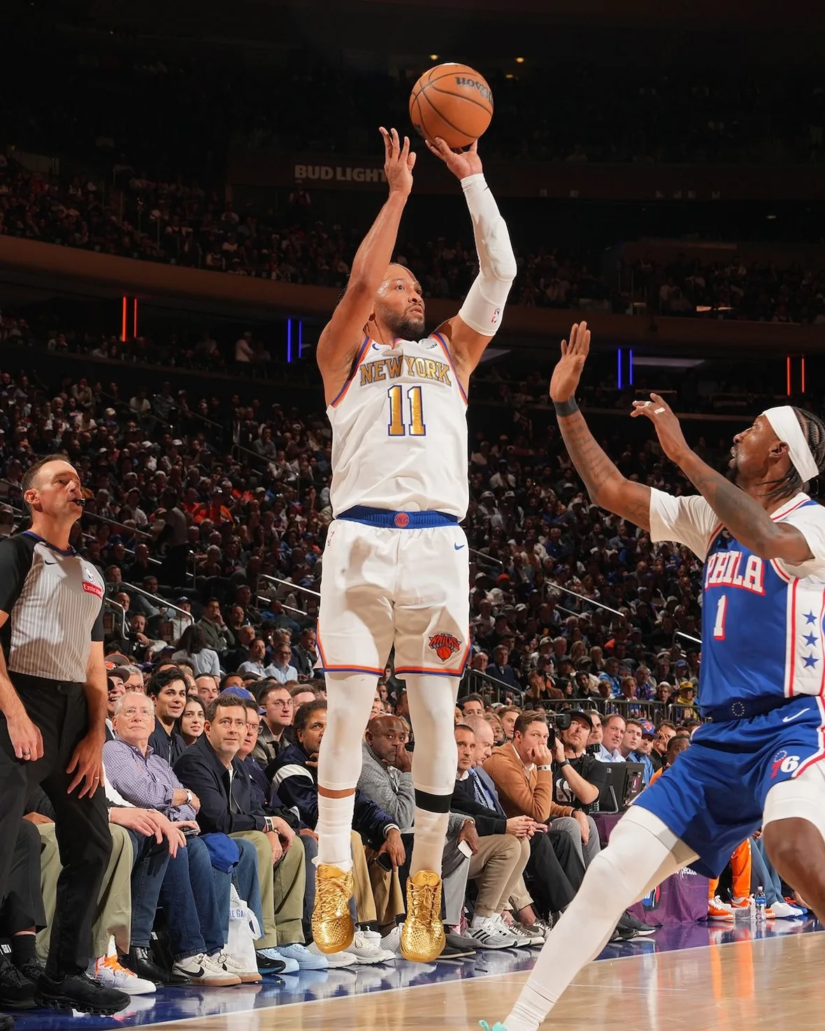 Basketball player in white New York #11 jersey shooting a jump shot in gold shoes, arena crowd behind, Ring Night