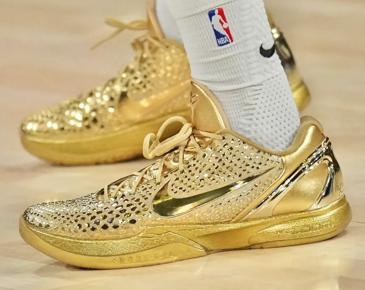 Lateral on-foot view of shiny gold perforated shoes with mirrored gold swoosh and ZOOM text on the midsole, Ring Night