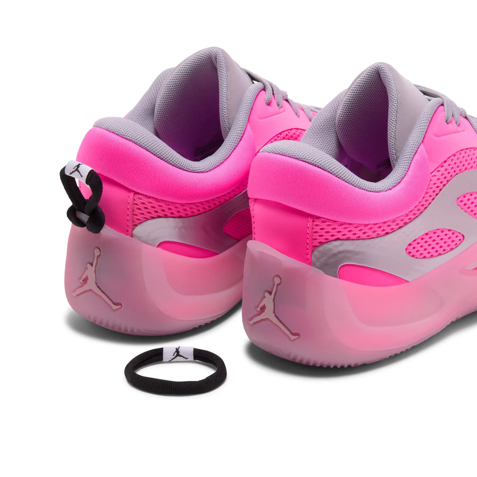 Heel detail of pair with Jumpman logos, plus a loose black hair tie on white, Pow Pink