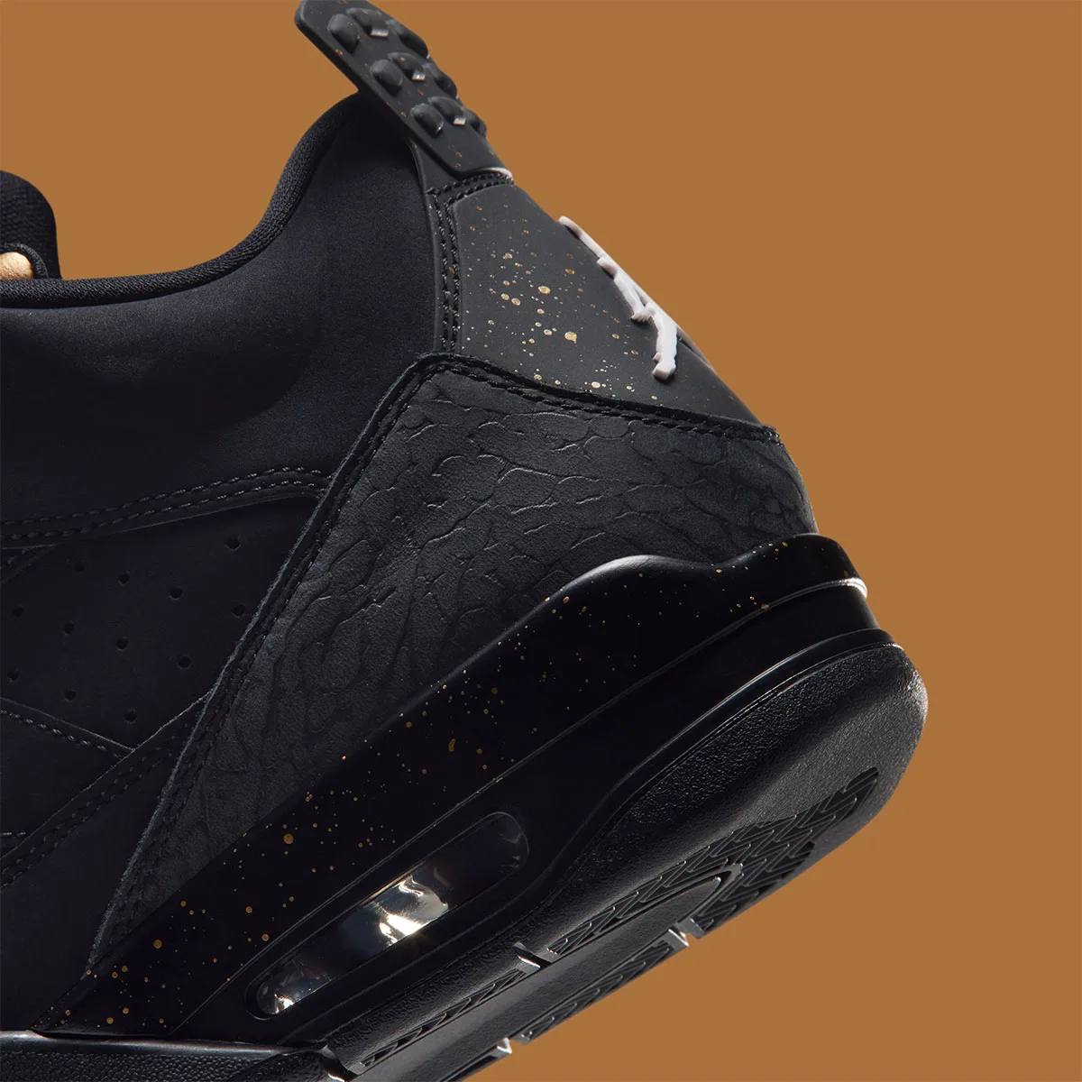 Detail of black heel with gold speckles, textured overlay, air window and white Jumpman logo, Gold Tongue