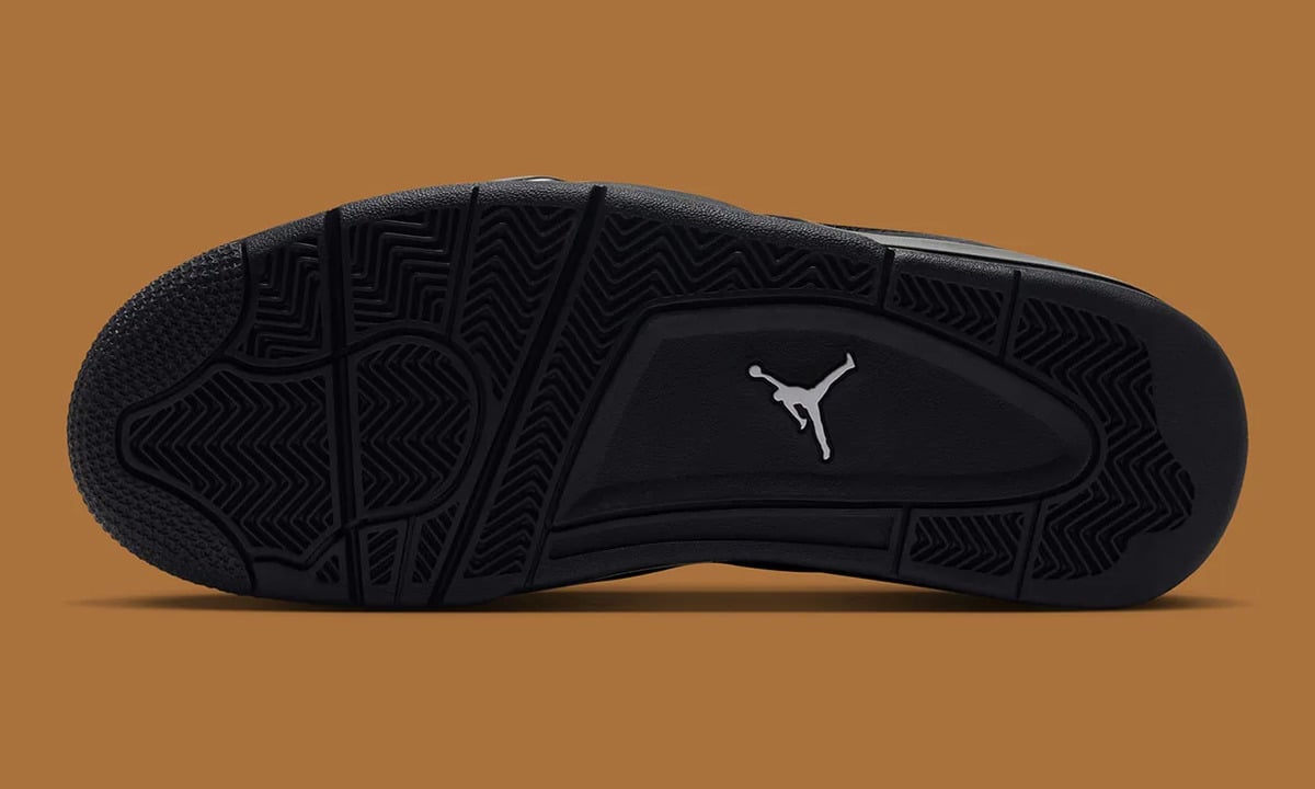 Outsole view of black herringbone-pattern traction with a grey Jumpman logo on tan background, Gold Tongue