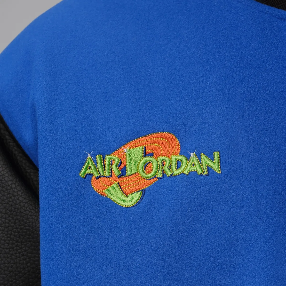 Detail of green and orange embroidered Air Jordan logo on blue wool chest, Varsity Royal/Black