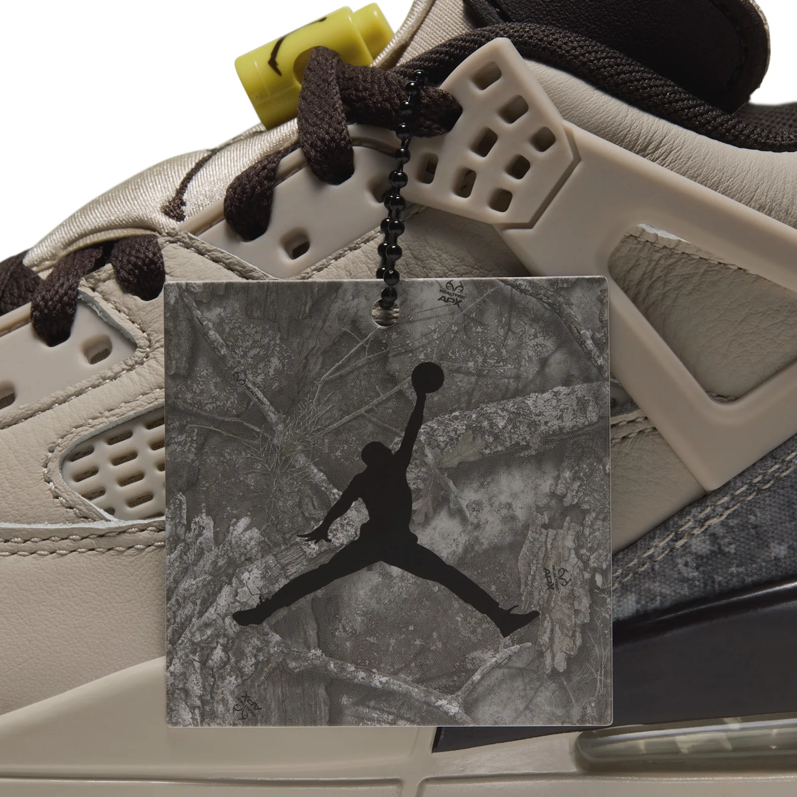 Detail of hang tag with Jumpman logo hanging over the lace area and tan perforated side panel, Realtree Camo