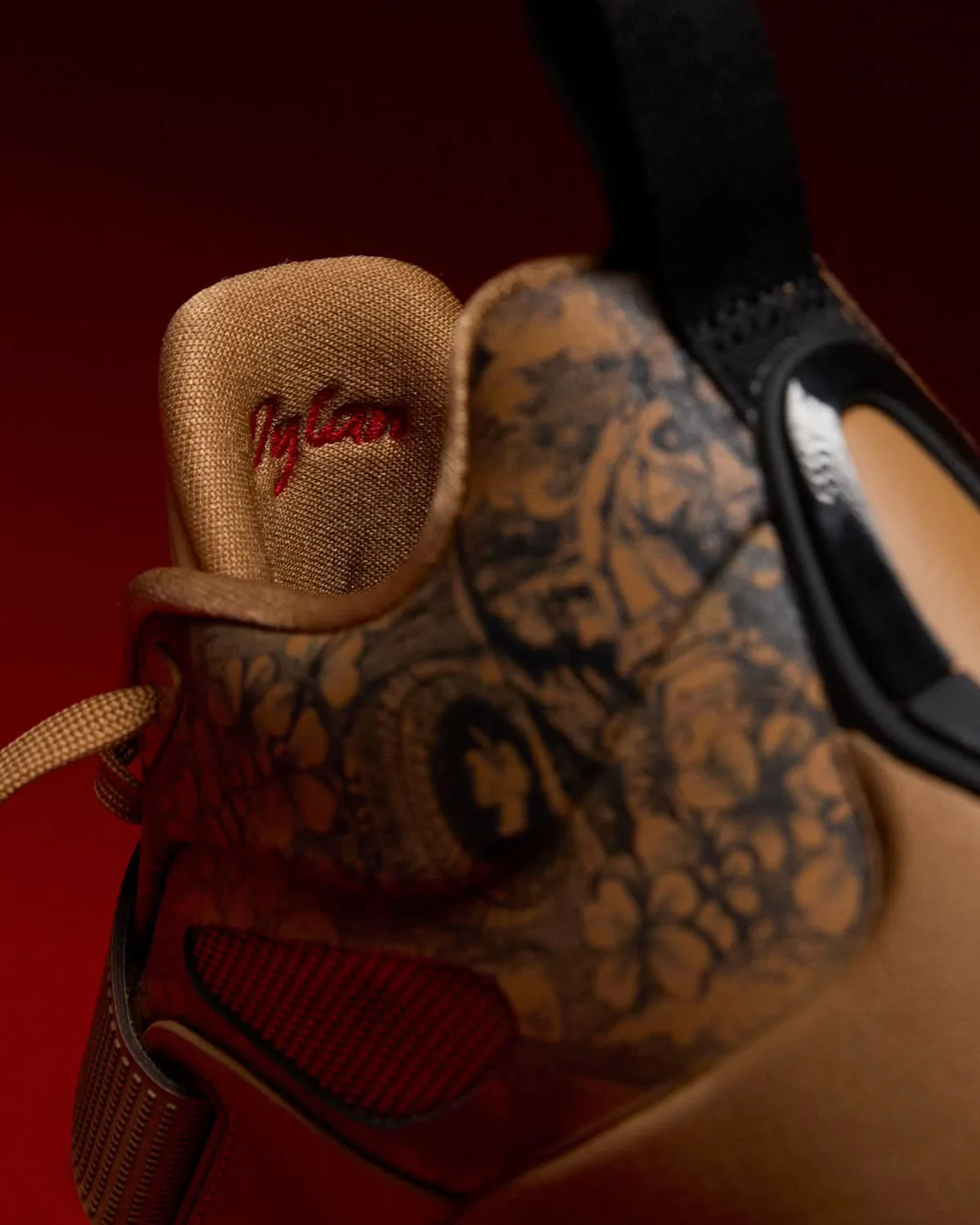 Detail of heel and tongue with red script text on tan lining, floral etched leather, black pull tab, Laser