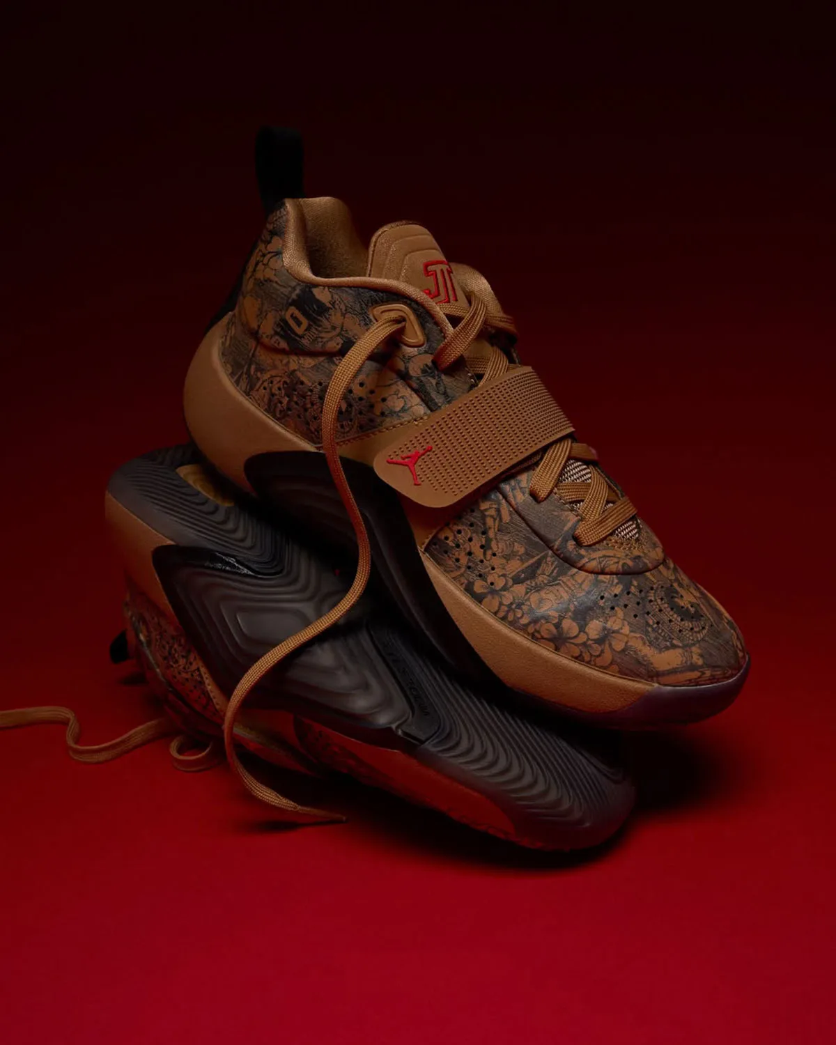 Stacked pair, one shoe resting on the other's dark outsole, tan etched floral upper, red backdrop, Laser