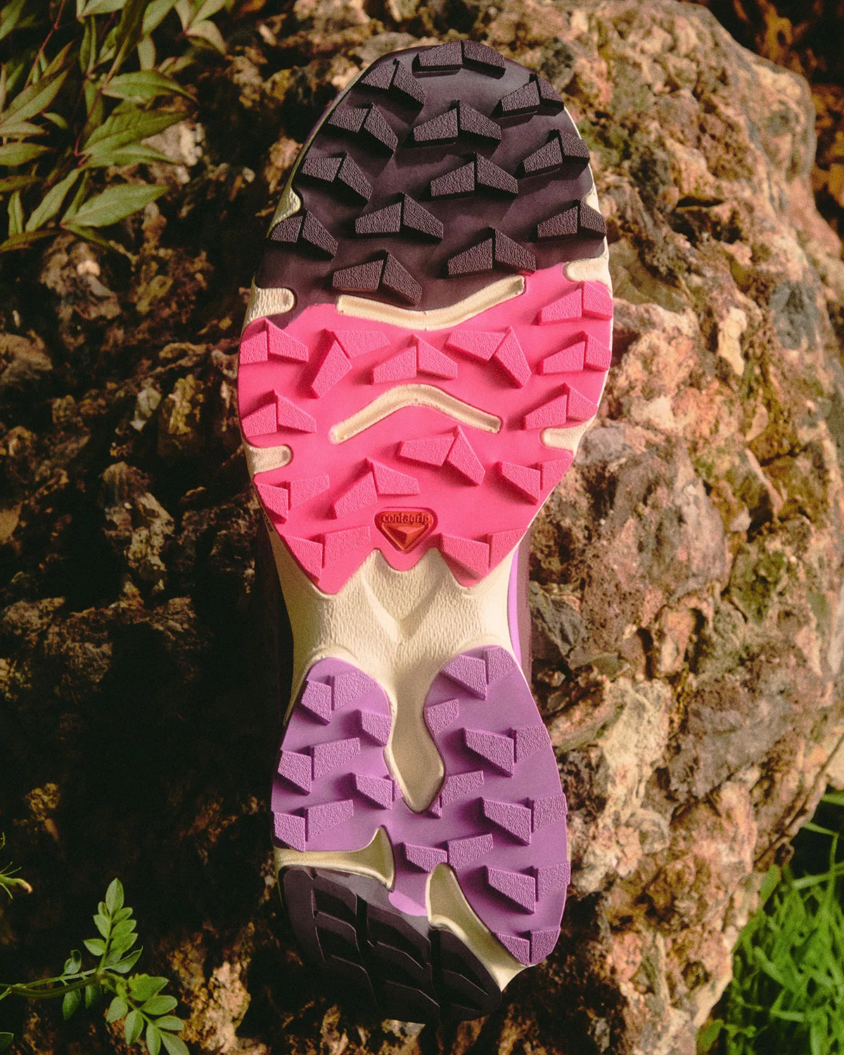 Outsole view with pink, purple and dark plum lugs on a rock surface, Contagrip logo visible, Winter 2026 Collection