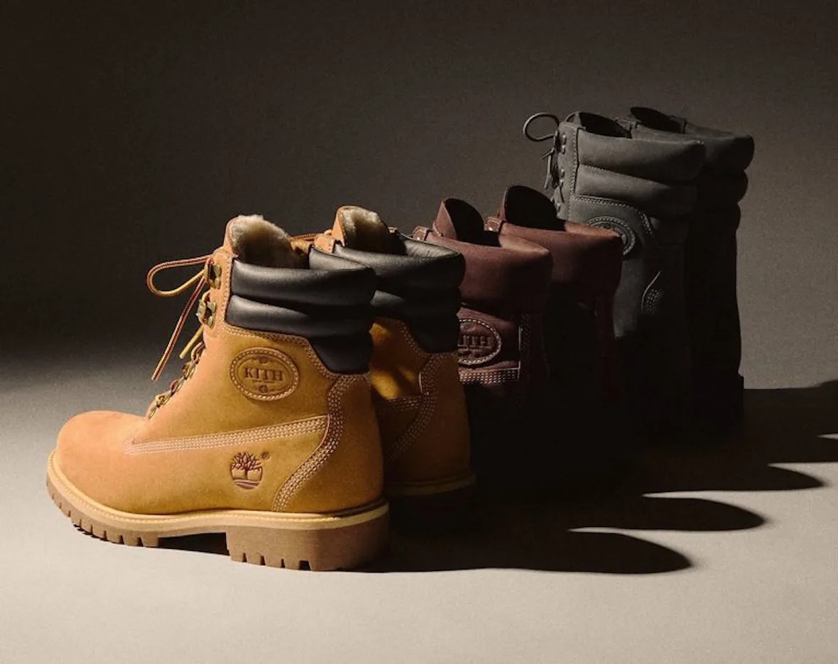 Three boots lined up in dim light, wheat pair with shearling collar in front, Wheat