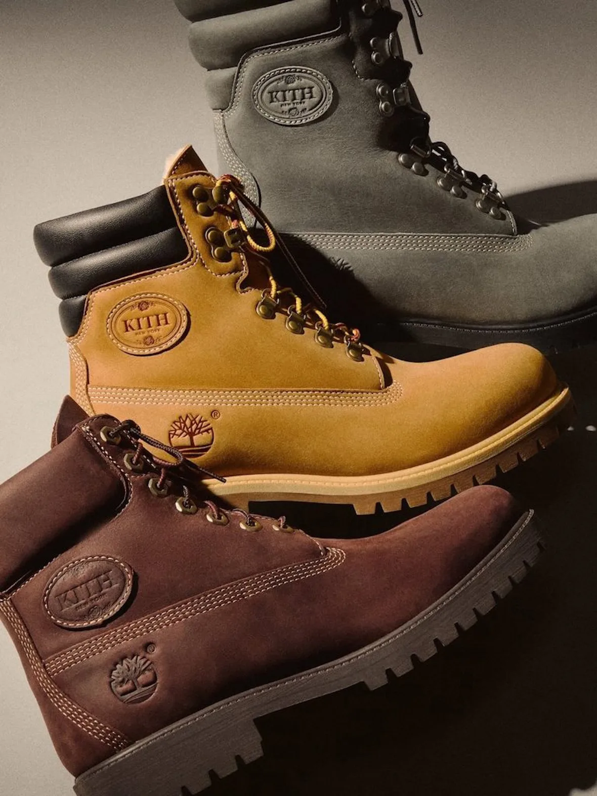 Stacked lateral view of wheat, brown and grey boots with Kith ovals and tree logos, Wheat