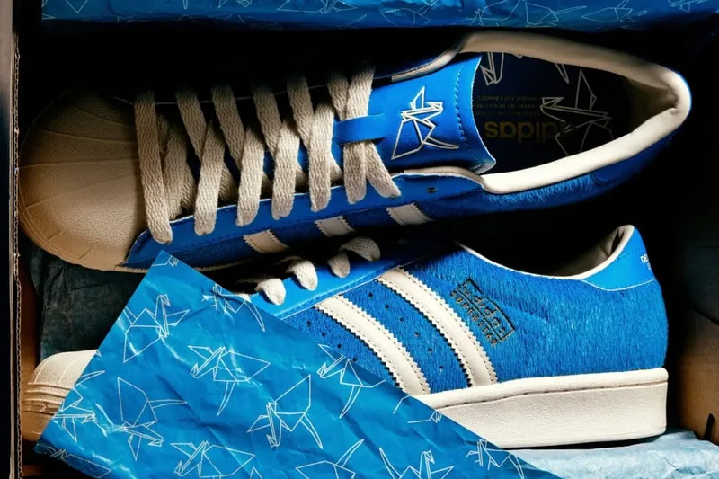 Wider crop of pair in box on blue origami crane tissue, cream stripes and shell toes, Blue