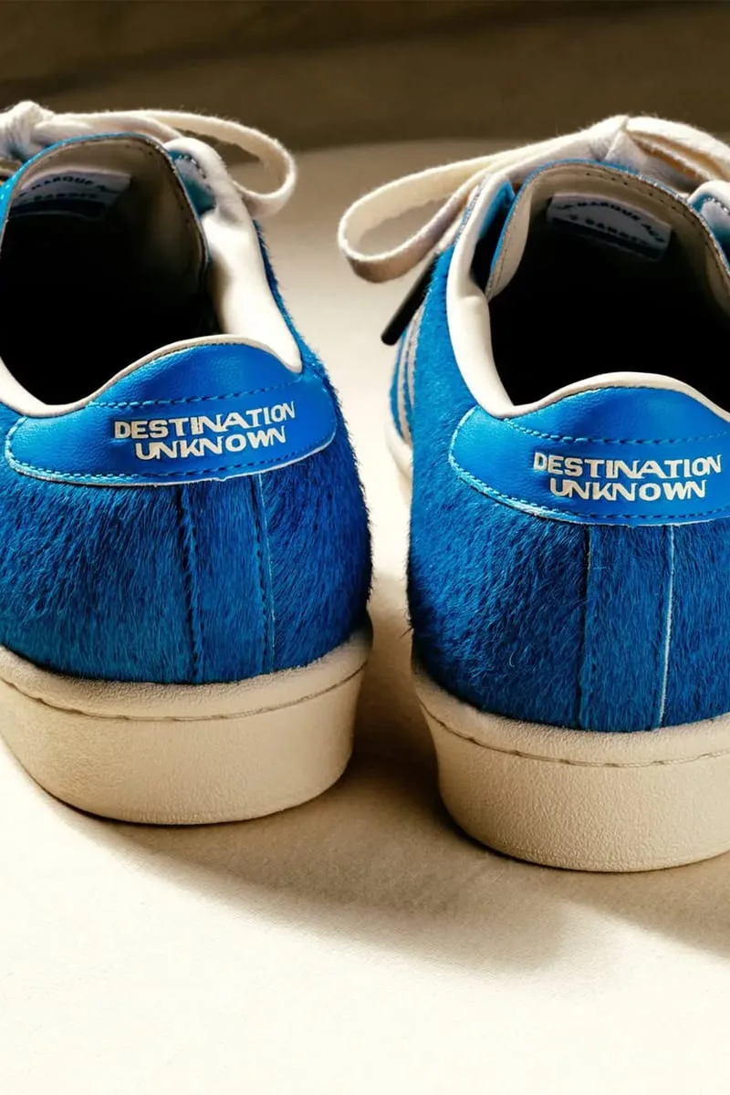 Heel view of pair with blue 'Destination Unknown' tabs, hairy blue upper, cream midsole, Blue
