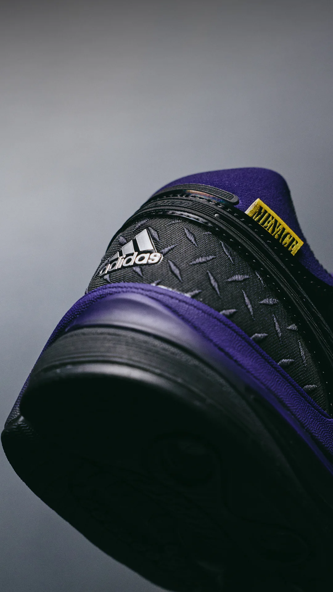 Heel close-up with a silver adidas logo on the diamond-plate counter and the yellow MENACE collar tab