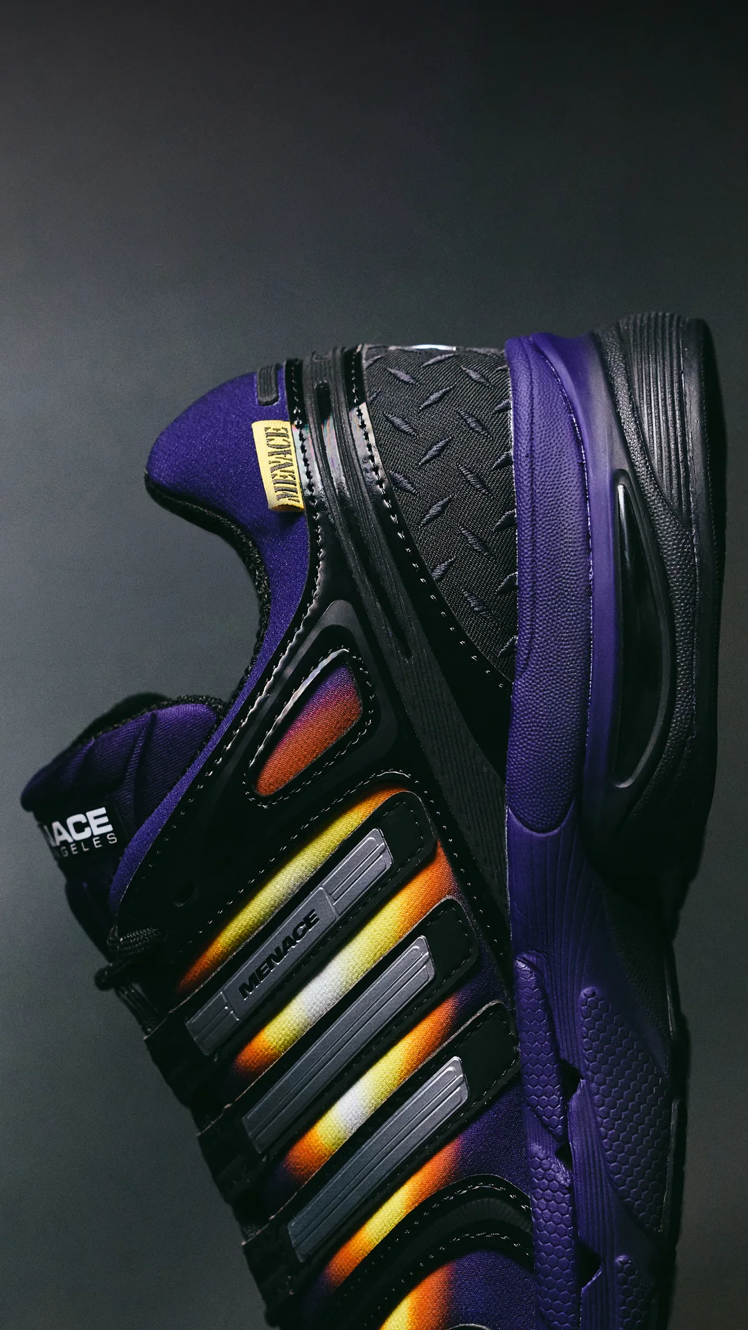 Side profile of the heel showing the diamond-plate overlay, yellow MENACE tab and silver stripes with a heat glow