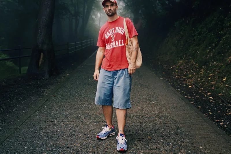 Full-length shot of person in red baseball tee and denim shorts wearing blue sneakers on a foggy path, Sean Wotherspoon Pack