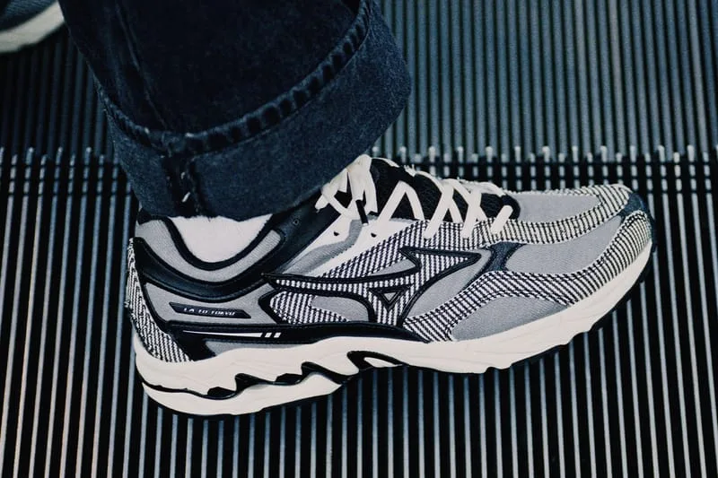 Lateral on-foot view of grey and black striped sneaker with white laces, on a black ribbed grate, Sean Wotherspoon Pack