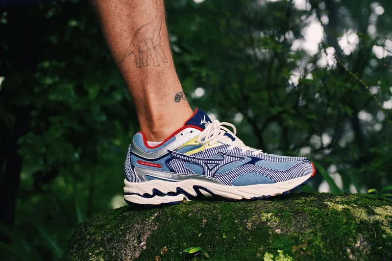 Lateral on-foot view of blue striped denim-look sneaker with red collar and white midsole, on a mossy rock, Sean Wotherspoon