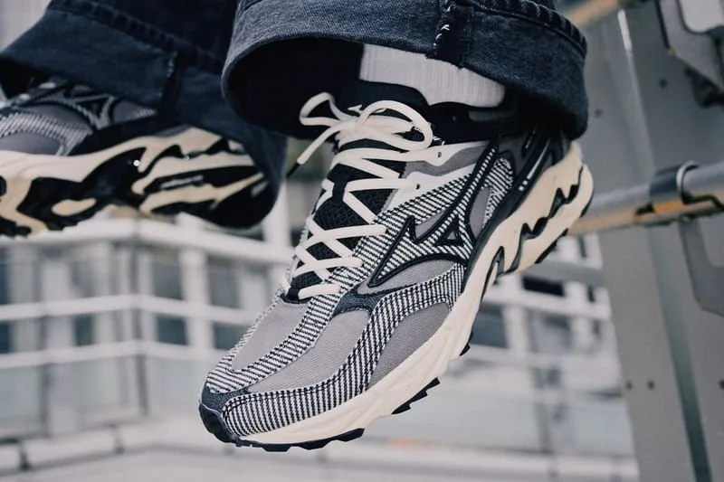 On-foot angled view of grey and black striped sneaker with cream laces, held up against a metal railing, Sean Wotherspoon