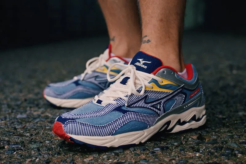 On-foot pair of blue striped sneakers with navy heel tab, red accents and cream laces on wet asphalt, Sean Wotherspoon Pack