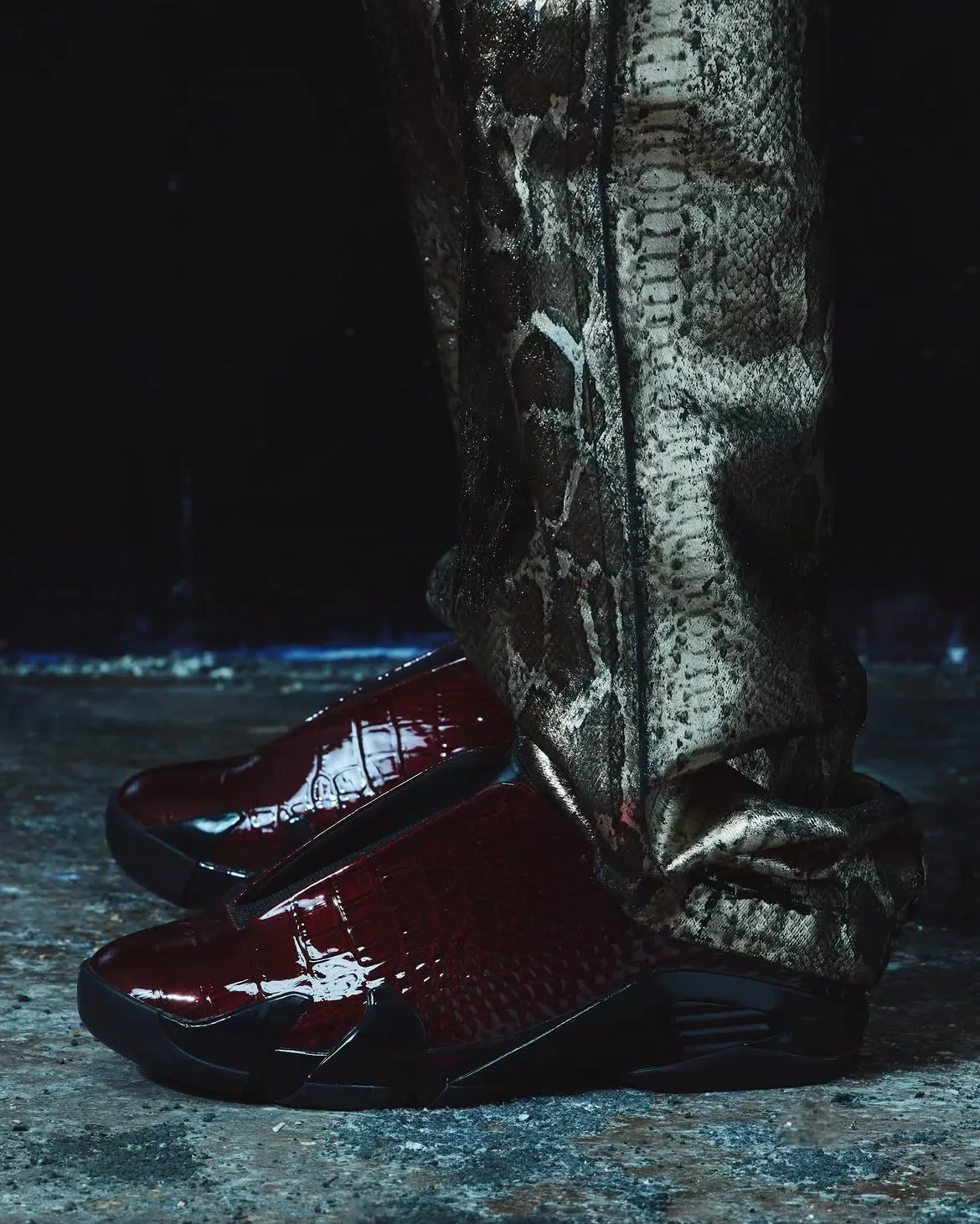 Lateral on-foot view of glossy burgundy croc-embossed mule with black sole, snakeskin-print trousers, Patent Croc
