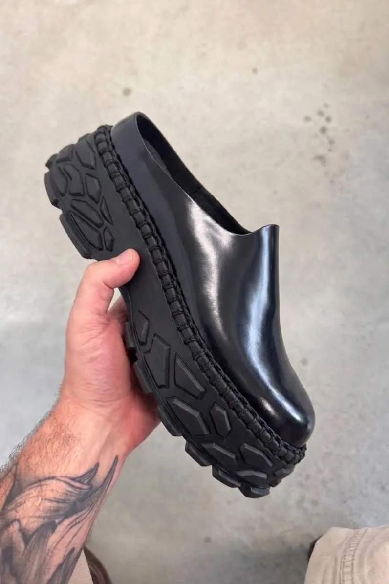 in-hand lateral view of glossy black slip-on with lugged sole, Terracotta