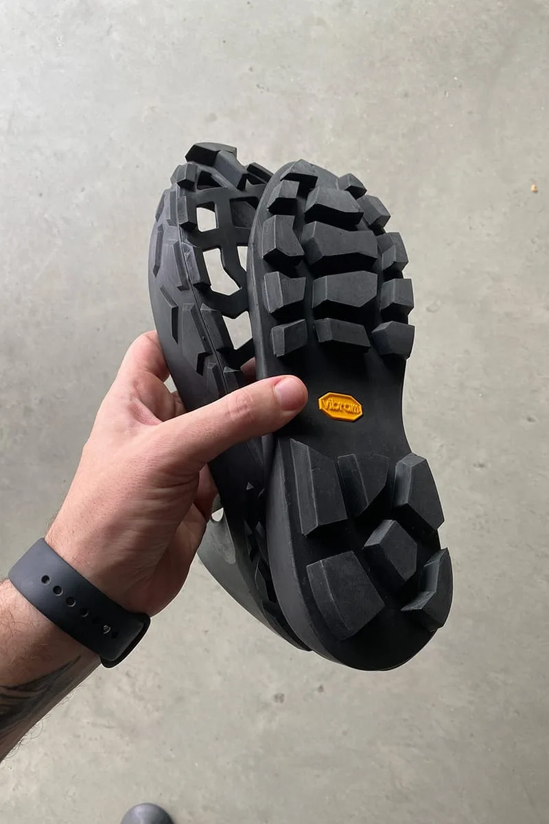 outsole held in hand showing chunky tread and orange Vibram tag, Terracotta