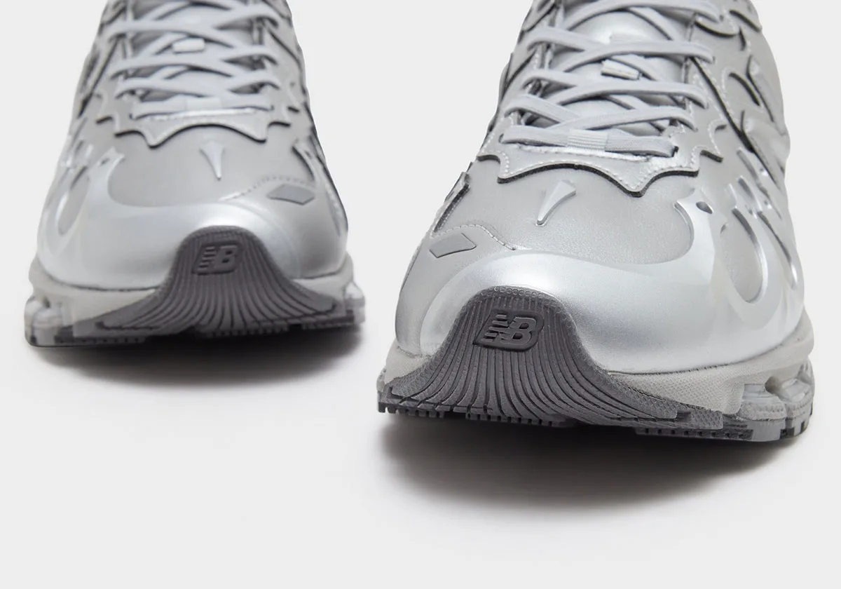 Toe-on detail of a silver pair with dark grey rubber toe caps and small NB logos, Liquid Metal