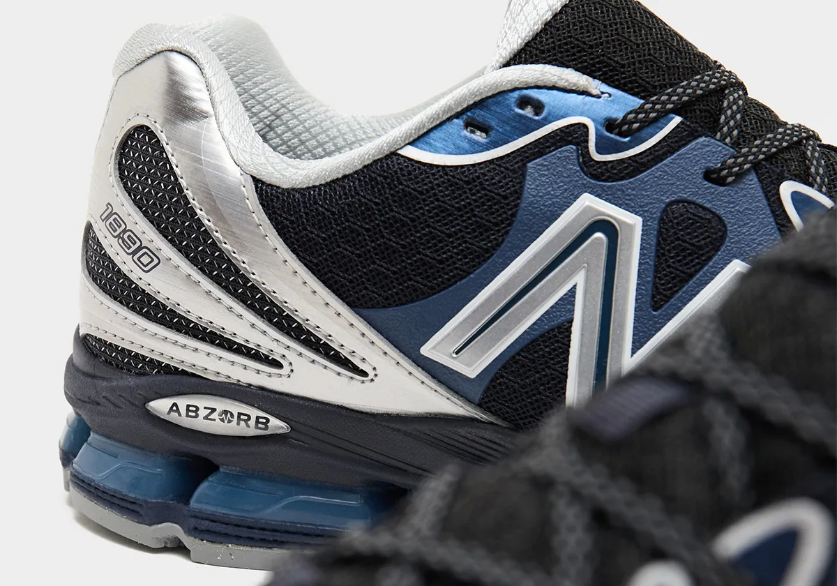 Detail of heel and midfoot, brushed silver heel, 1890 text, ABZORB badge, silver N, blurred laces in foreground, Metallic