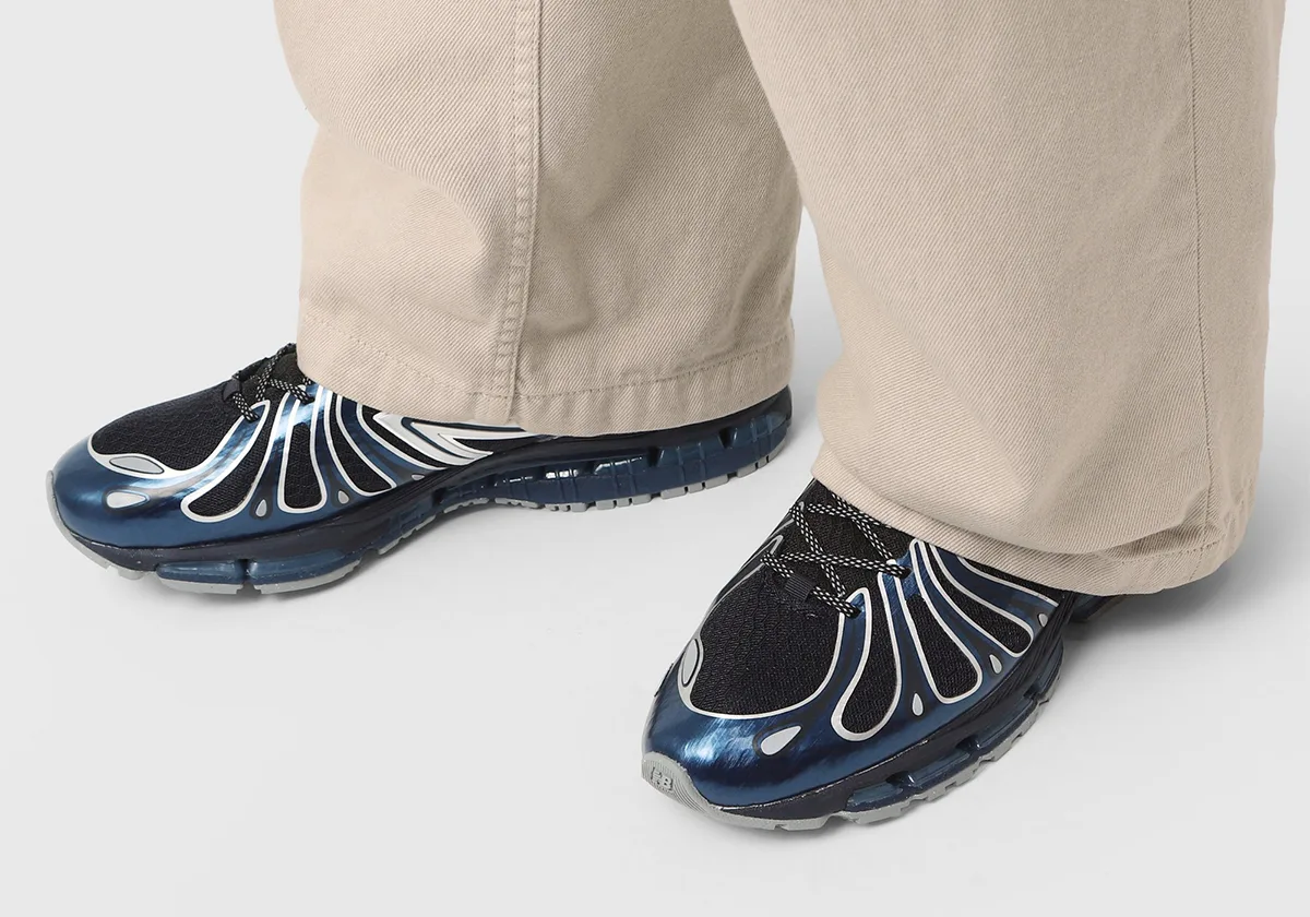 On-foot view in beige wide-leg trousers, glossy blue toe caps with silver outlines and black laces, Metallic Blue