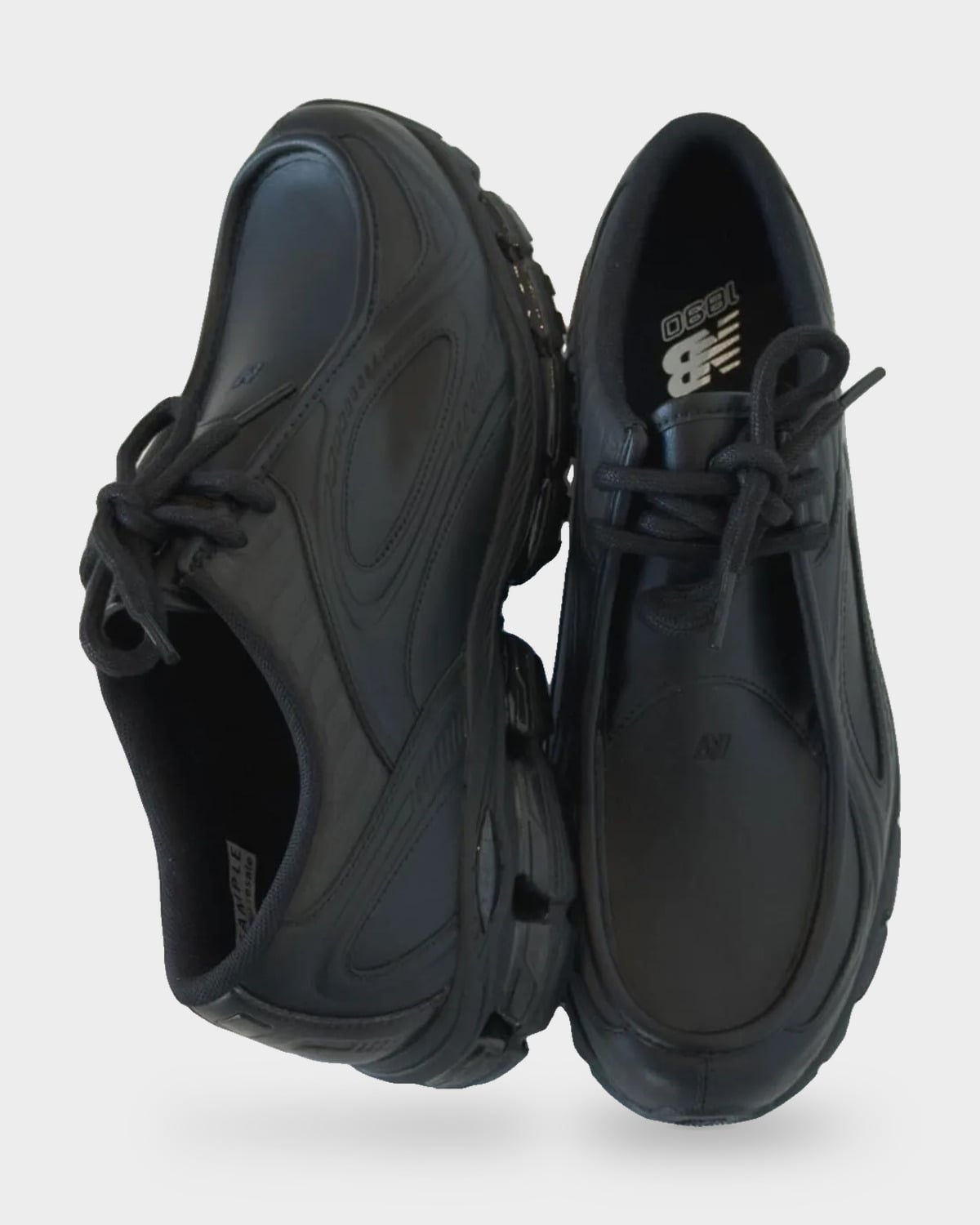 Top-down pair, one shoe tilted, with black laces and NB 1890 logo on the insole, Black Leather