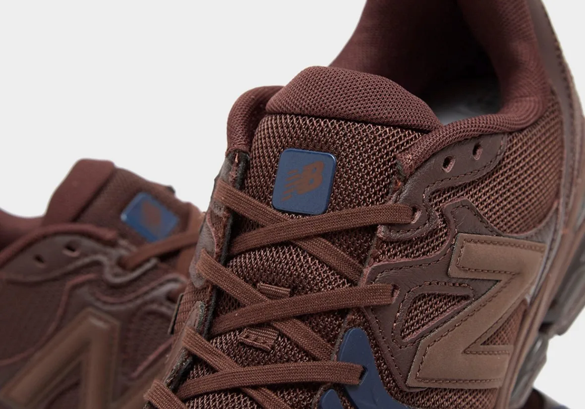 Detail of brown mesh upper with navy New Balance tongue tag, brown laces and tan N logo, Brown/Navy