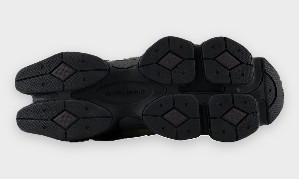 Outsole view of black rubber sole with diamond-shaped lugs and New Balance text, Balance 9060 Trail