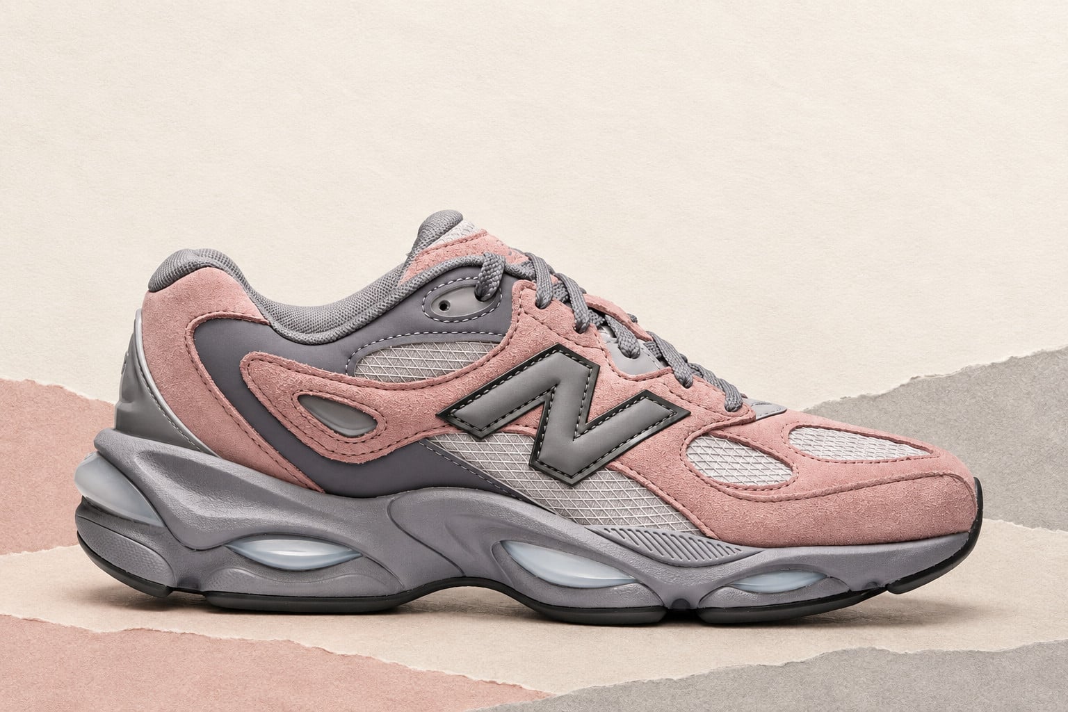Lateral view on torn pink, beige and grey paper, pink suede with grey N logo and mesh, New Balance 983 “Pink/Grey”