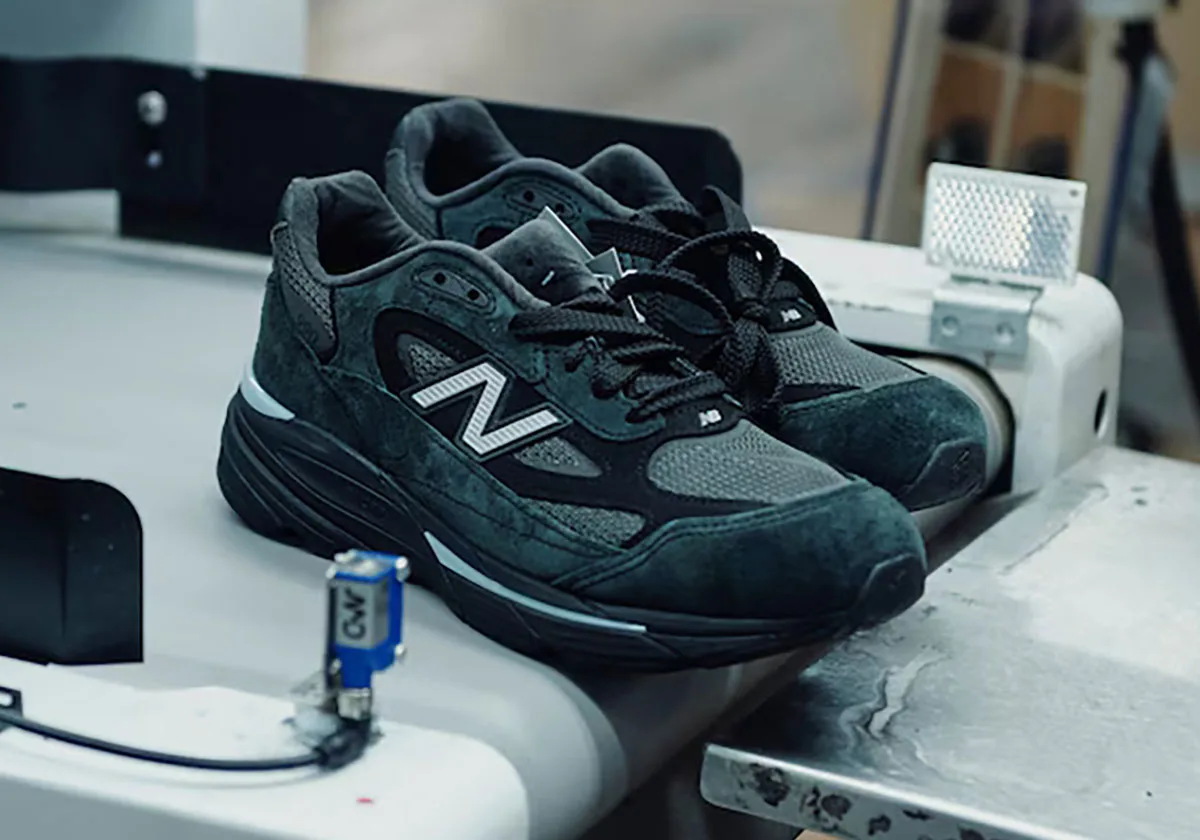 Lateral view of black suede pair with grey N logo on a workshop conveyor, Black/Silver