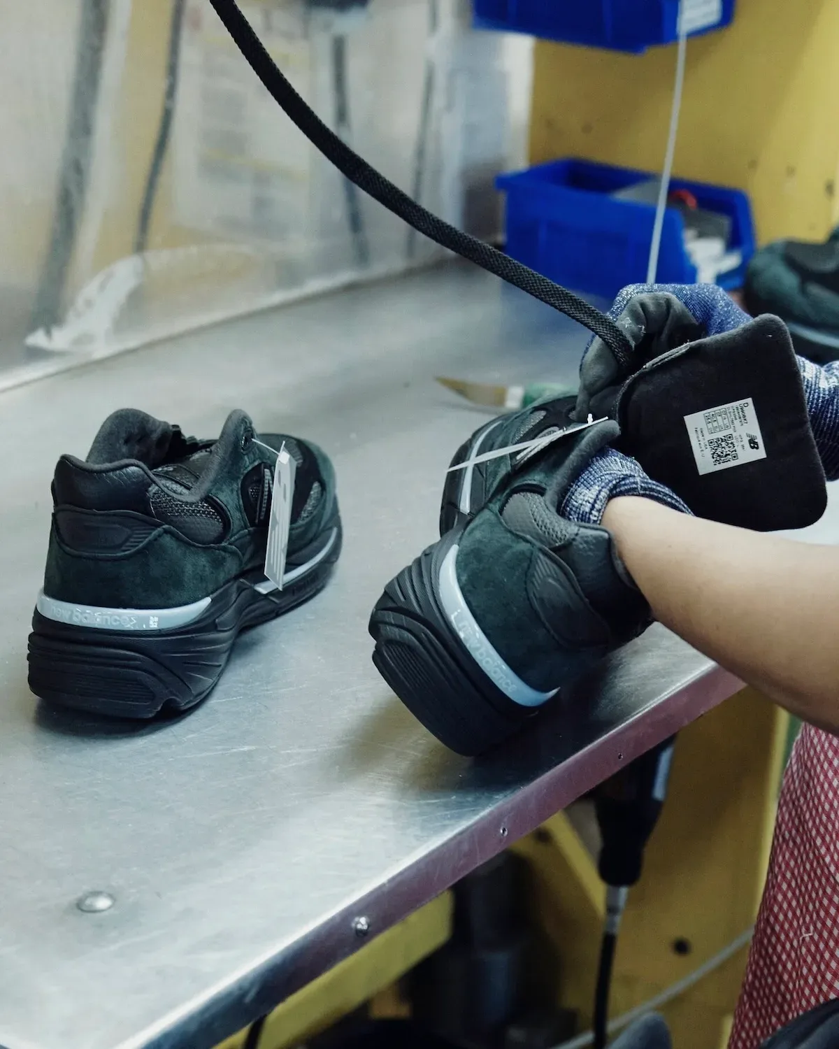 Heel view of a pair on a workbench, with pale blue trim and tongues open, Black