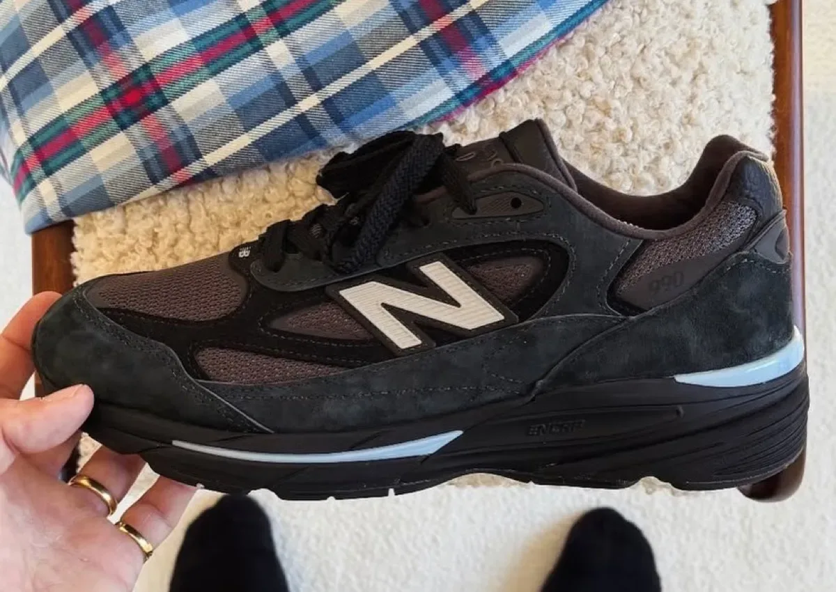 Lateral view in hand with a white N logo and pale blue sole accents, Black