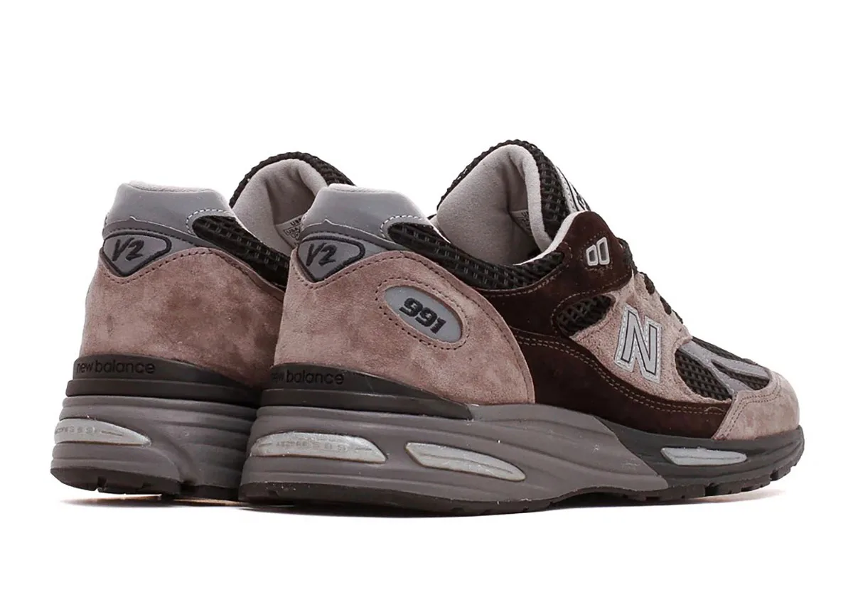 Rear three-quarter view of a pair with taupe suede heels and V2 text, Iron/Mulch