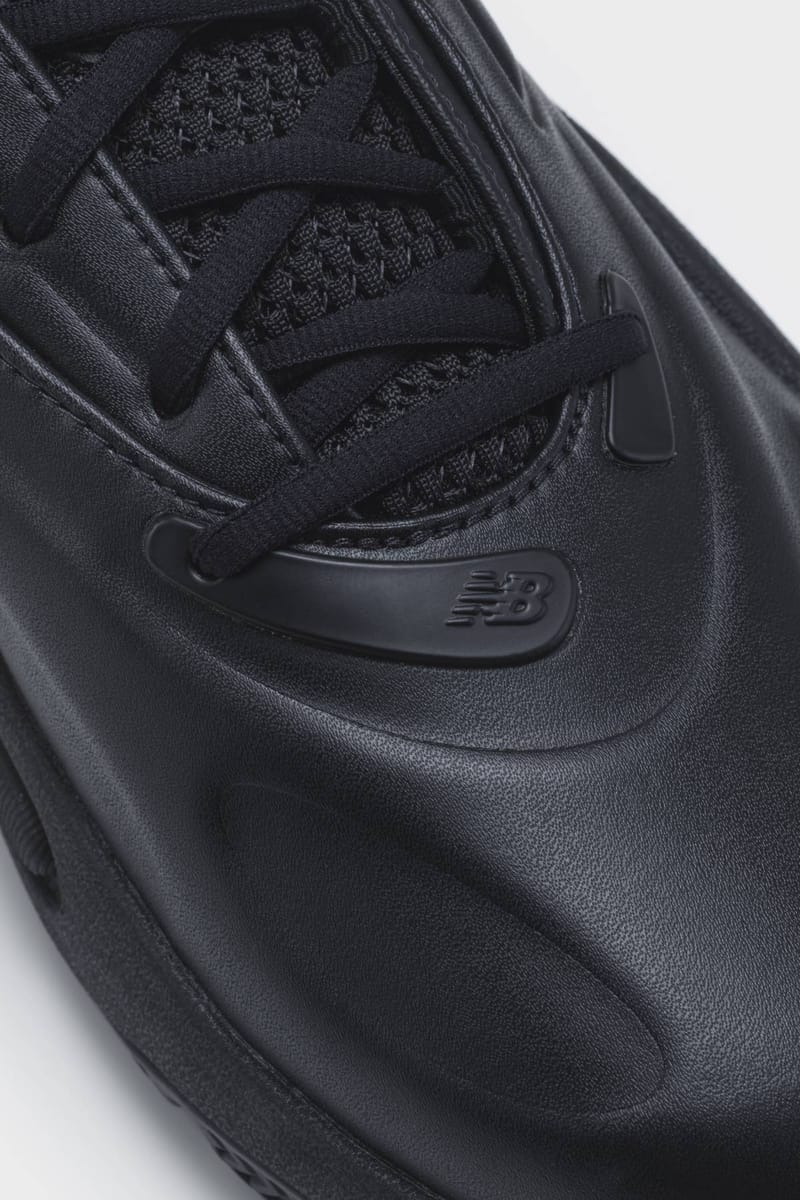 Close-up of black leather and mesh upper with black laces and an embossed New Balance logo on the lace eyelet, Watanabe MAN