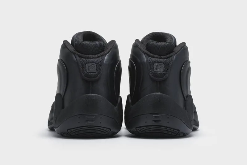 Heel view of an all-black pair showing small New Balance logo patches and black outsoles, Watanabe MAN P400