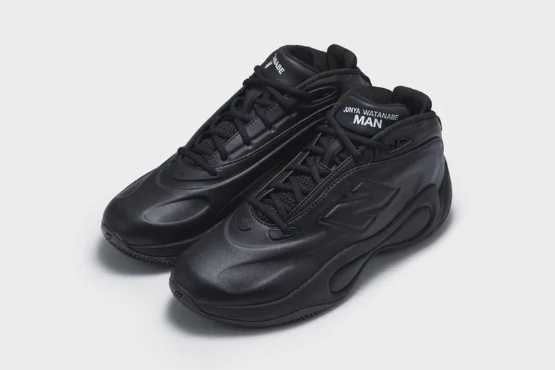 Three-quarter view of an all-black pair with black laces and white Junya Watanabe MAN tongue text, Watanabe MAN P400