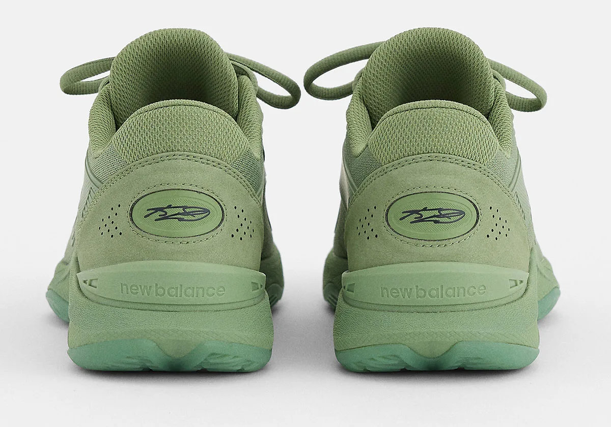 Heel view of green pair with oval signature badge and new balance text on heel clip, Balance Kawhi 5