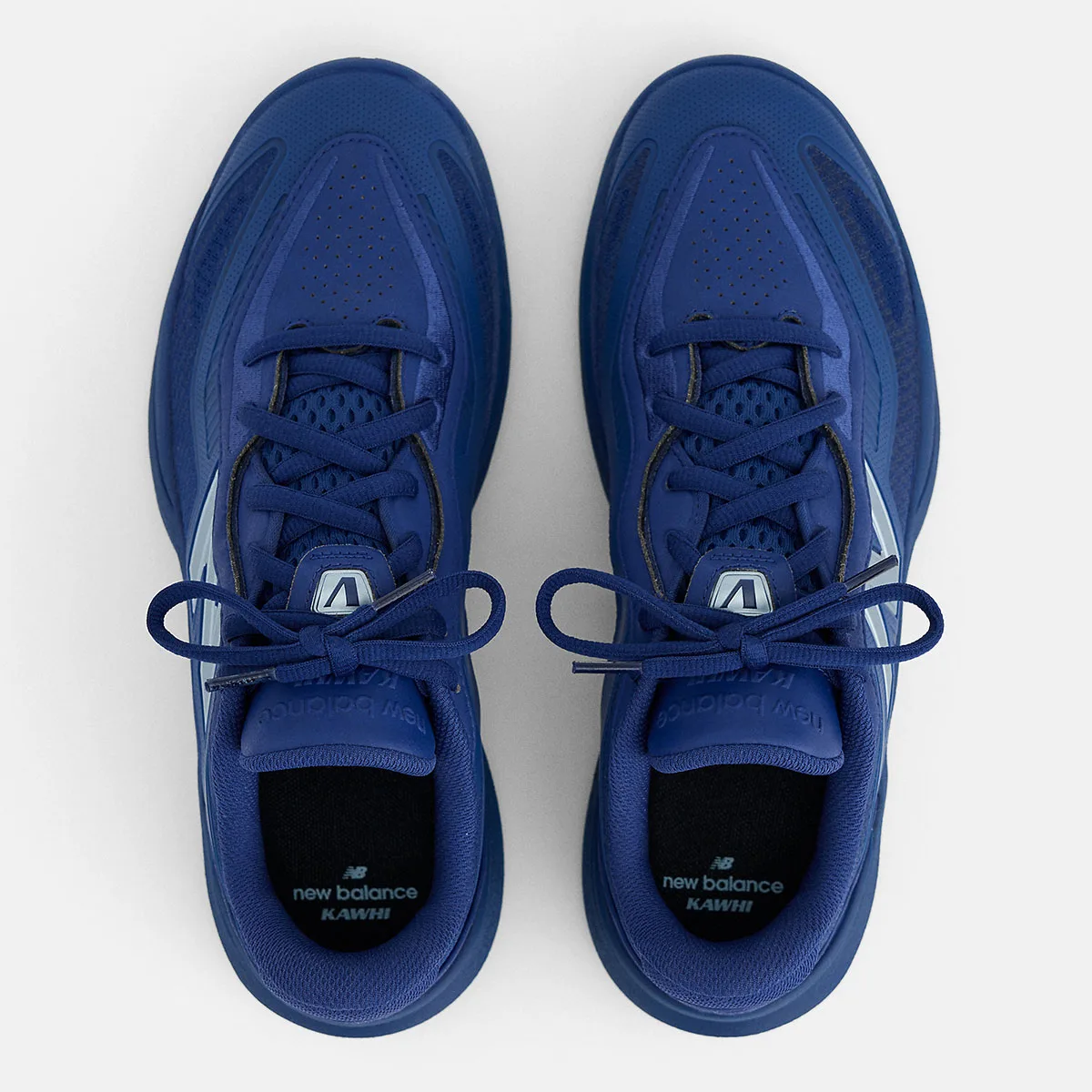 Top-down view of blue pair with bow-tied laces, perforated toe and black insoles marked Kawhi, Balance Kawhi 5
