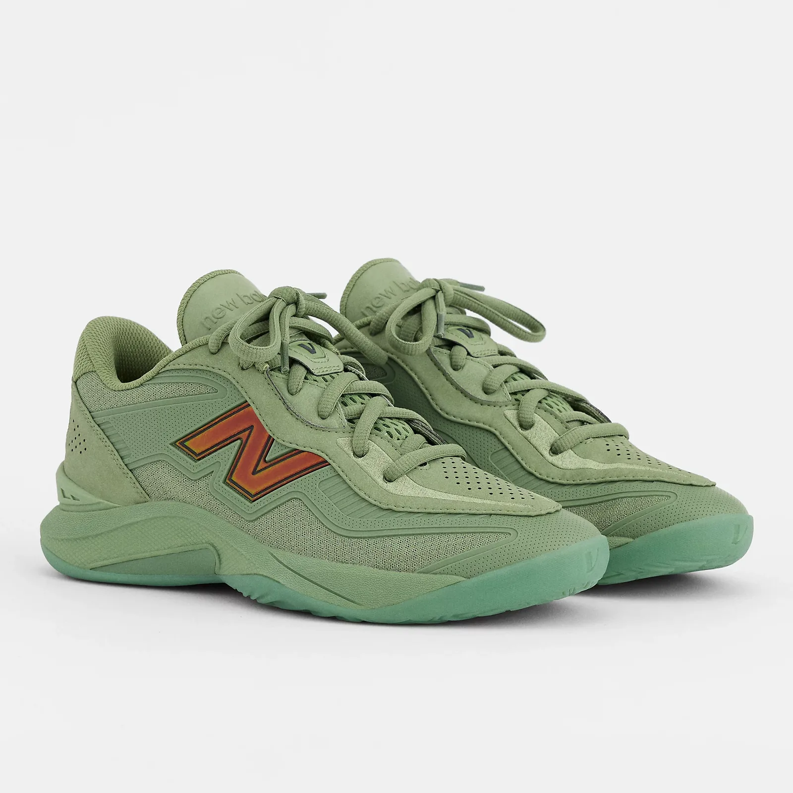 Pair at an angle on white, tonal green suede and mesh with iridescent orange-red N logos, Oregano