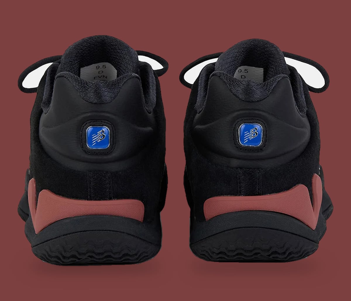 Heel view of pair, black uppers with blue New Balance logo badges, red-brown heel accents, Red Rock
