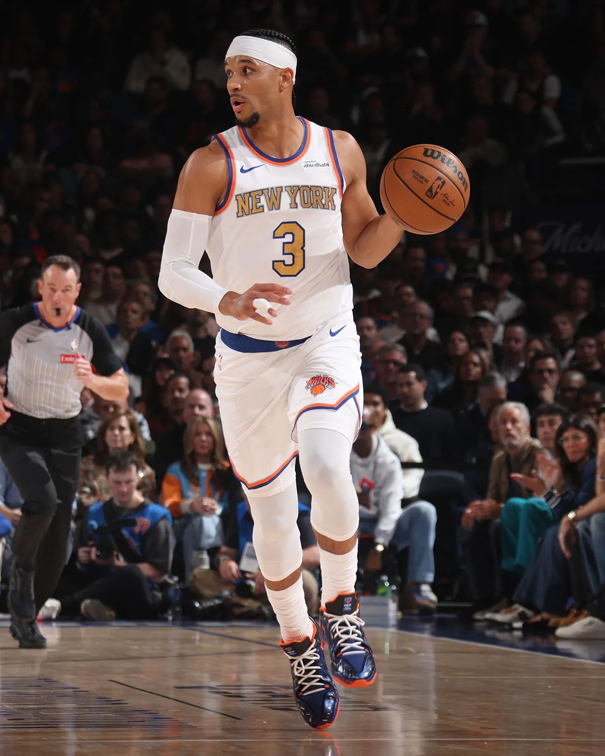 On-foot shot of a player in a white New York jersey dribbling, wearing blue and orange sneakers, crowd behind, Confetti