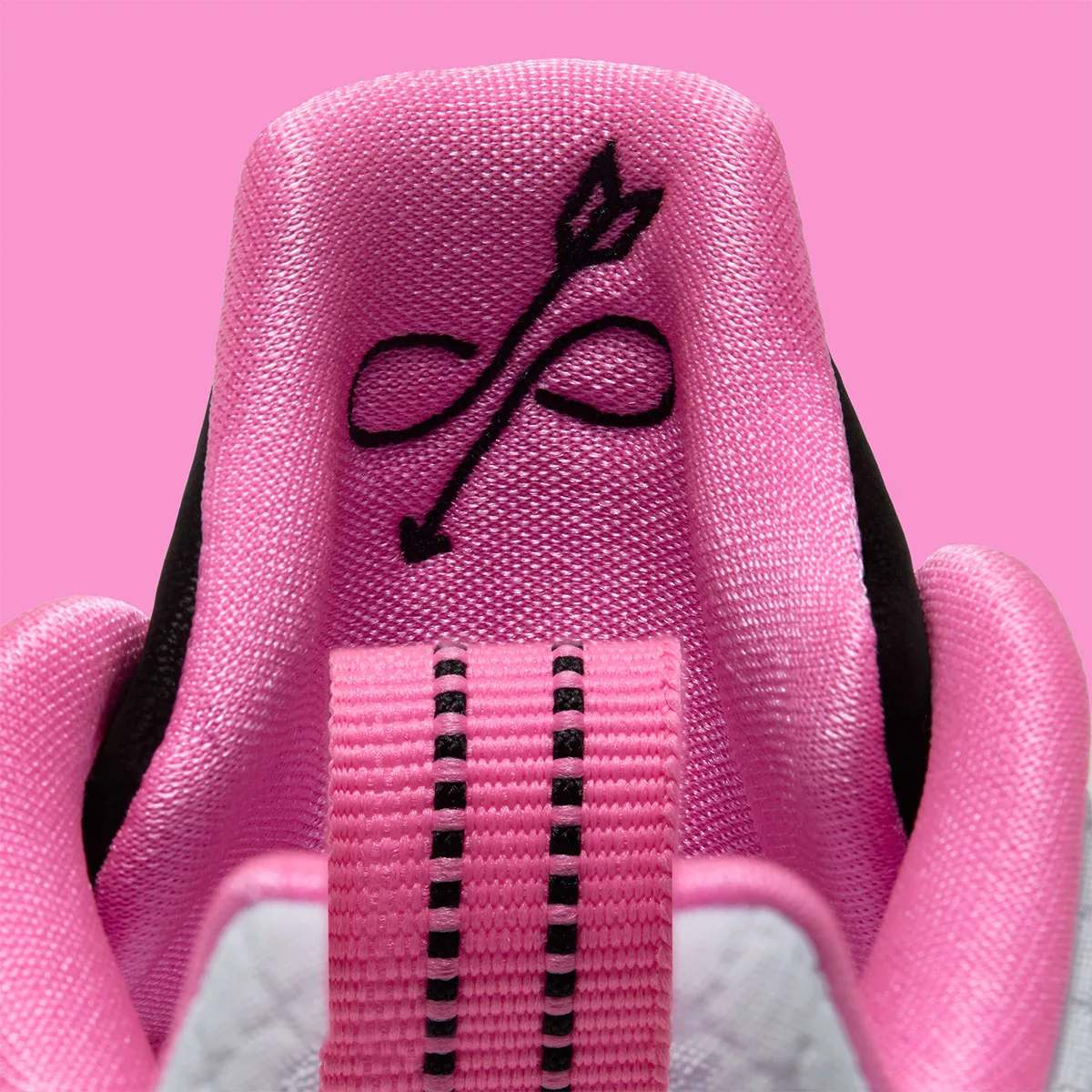 Detail of pink tongue with black arrow-through-infinity embroidery and pink pull tab with black stitching, Cruise Control