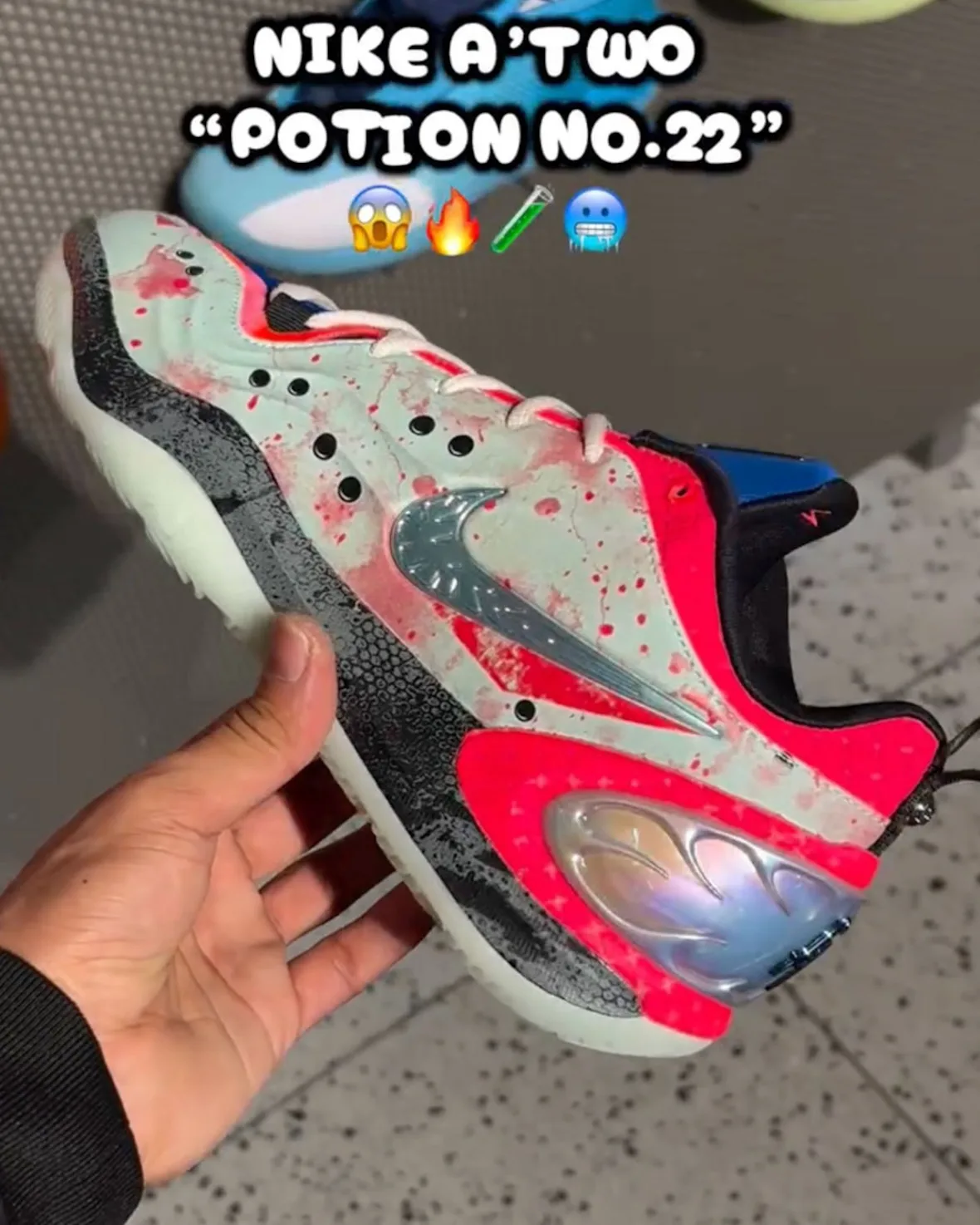 Lateral in-hand view of mint and pink splattered shoe with silver swoosh, black speckled midsole and iridescent heel pod