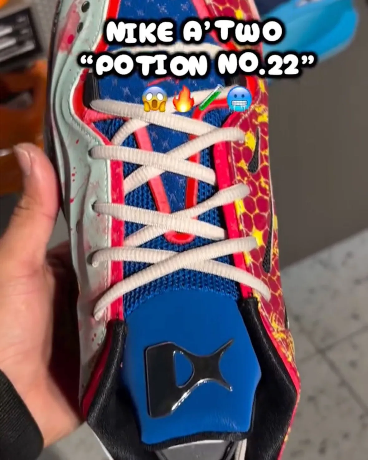 Top-down view of white laces over blue mesh tongue, mint splattered side, red honeycomb side and blue tongue tab, Potion No.