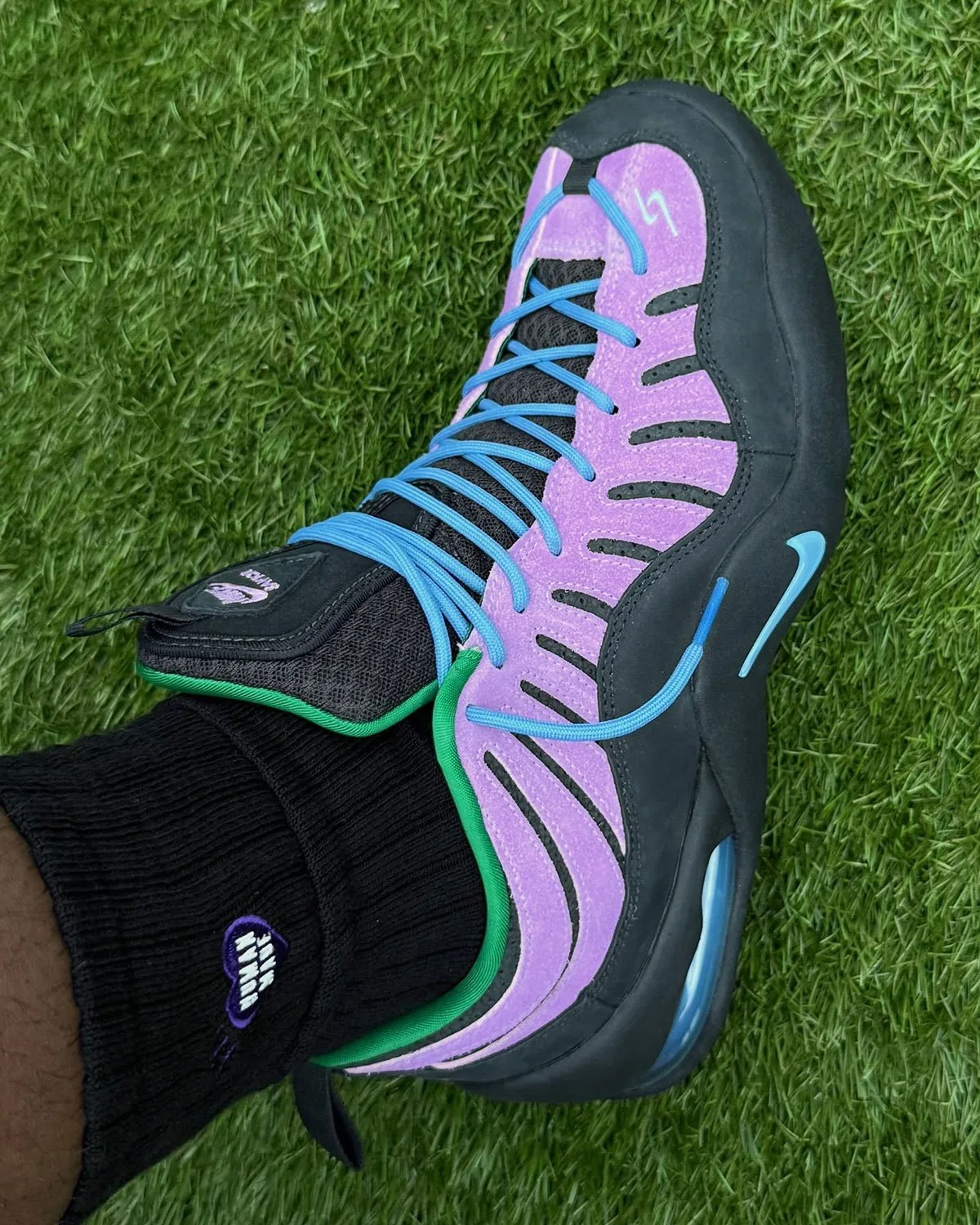 On-foot top-down angle on grass: purple suede, blue laces, black sock with heart logo, Purple Stardust
