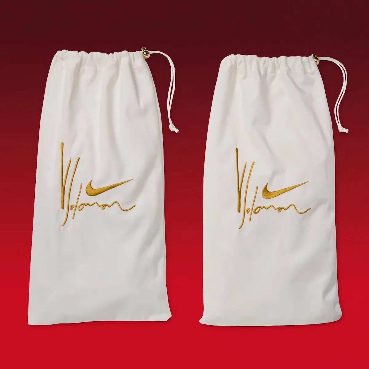 Pair of white drawstring dust bags with gold embroidered signature and swoosh, gold bead pulls, Gym Red