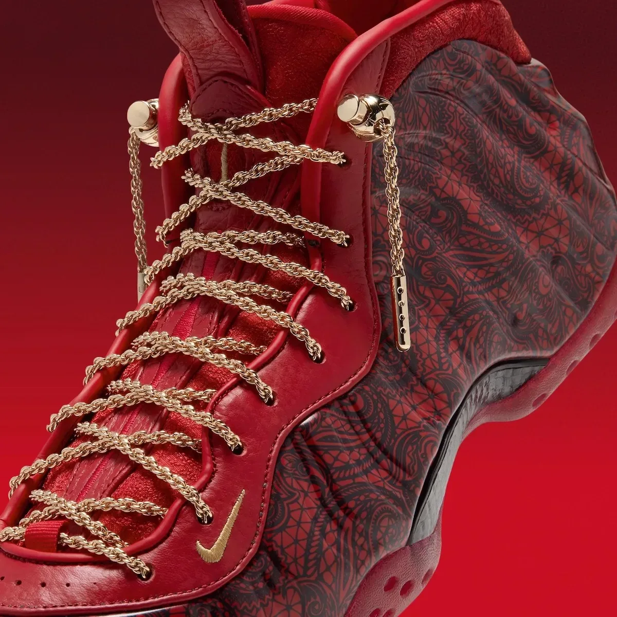 Detail, angled front of shoe, gold chain laces, gold swoosh, black lace-print foam shell, Gym Red