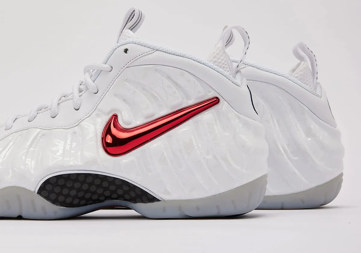 Detail, lateral heel of white shoe with red chrome swoosh and black mesh panel, Ohio State